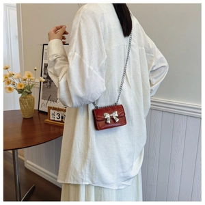 Detailed view of mini red chain bag with silver metal bow and flap closure