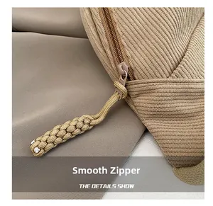 Detail view of khaki corduroy fabric featuring a smooth zipper and woven rope puller