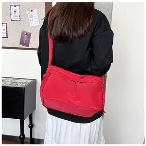 Rear view of a red large nylon messenger bag with double zippers and wide strap