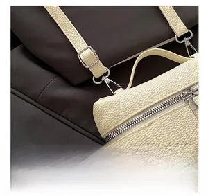 Detail of silver metal hooks and textured lychee leather on cream crossbody bag