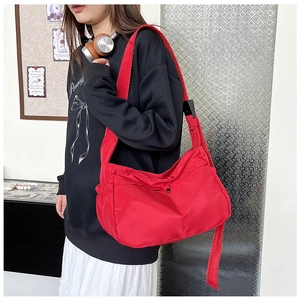 Macro view of red nylon messenger bag featuring adjustable straps and zipper pockets