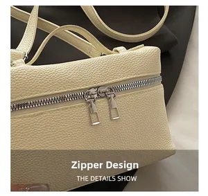 Detail view of smooth silver double zippers on cream lychee grain leather handbag