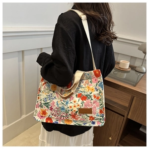 Detail of floral canvas tote bag with adjustable strap and leather fashion brand tag