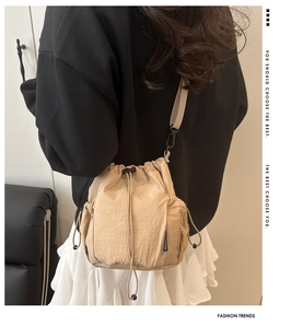 Detail of nylon bucket bag featuring a mesh side pocket and adjustable crossbody strap