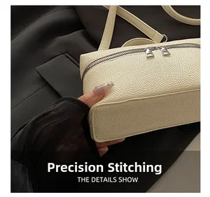 Close-up of precise stitching on off-white lychee pattern leather handbag with dual zippers