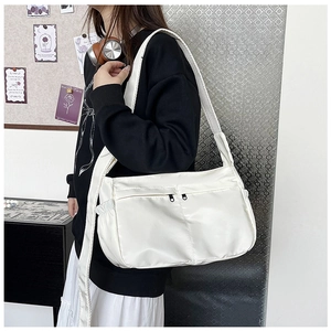 Detailed view of a white nylon commuter crossbody bag with black dual zippers and wide straps