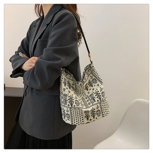 Détail du sac bandoulière en toile florale avec bandoulière cuir noir et boucles dorées