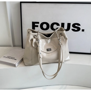 Detail of off-white glossy faux leather tote bag with metal twist lock and chain strap