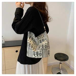 Détail d'un grand sac seau en toile à imprimé floral porté à l'épaule par un mannequin