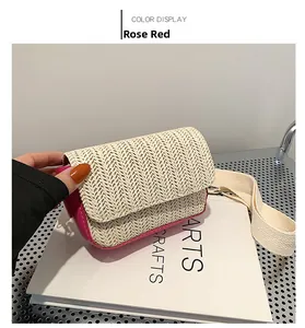 Detail view of woven straw crossbody bag in rose red and ivory with canvas strap