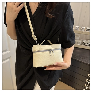 Beige pebble leather bag with top handle and silver zipper shown on a model