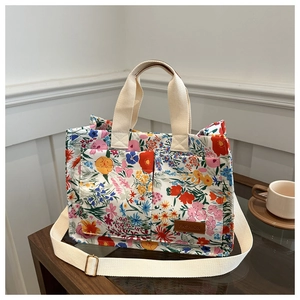 Detail showing colorful floral fabric, canvas straps, and leather logo on the tote bag