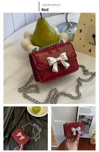 Detail of red oil wax leather mini bag featuring a large silver metallic bow and chain