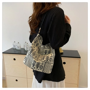 Détail du sac seau en toile avec motif floral noir et blanc porté par un mannequin