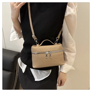 Detailed view of coffee-colored lychee pattern handbag with silver zippers on a model