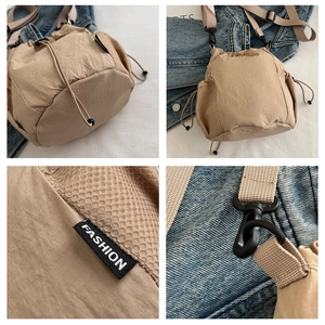 Detail of beige nylon drawstring bucket bag with mesh panels and adjustable strap