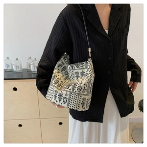 Photo lifestyle d'un sac seau imprimé de style chinois porté avec une chemise noire chic