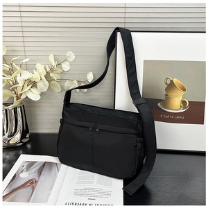 Close-up of black nylon crossbody bag featuring parallel zipper pockets and wide strap