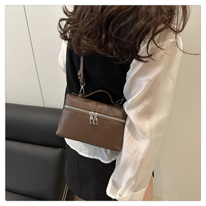 Litchi pattern leather handbag with silver double zippers shown on shoulder of a model