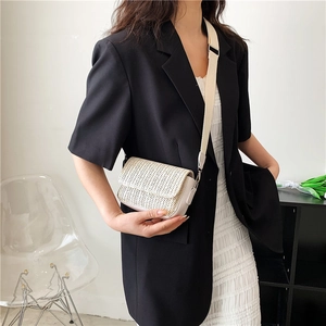 Chic beige woven crossbody bag with leather trim worn by model in minimalist studio