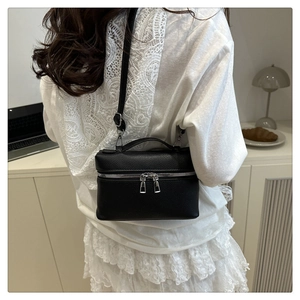 Detail of black lychee grain leather mini bag with silver metal zippers and top handle
