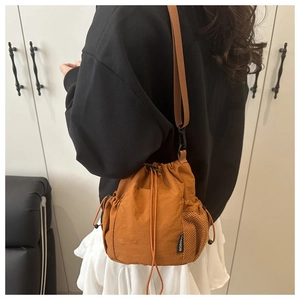 Close-up of brown nylon drawstring bucket bag with mesh pocket and adjustable shoulder strap