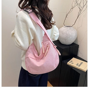 Pink corduroy crescent bag detail featuring braided zipper and wide shoulder strap style
