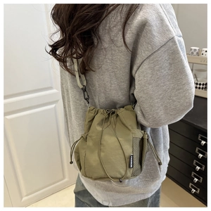 Olive green nylon bucket bag featuring side mesh pocket and fashion label detail