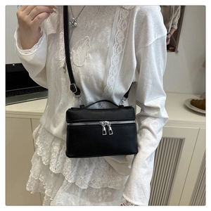 Detail of black lychee grain leather vanity bag with silver zippers and adjustable strap