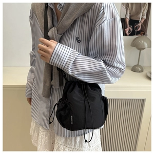 Close-up of black nylon drawstring bag showing mesh side pocket and fashion label