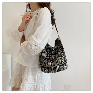 Détail d'un sac seau en toile noire avec imprimé floral blanc et finitions dorées