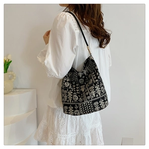 Détail d'un sac cabas bohème à fleurs porté avec une robe blanche brodée