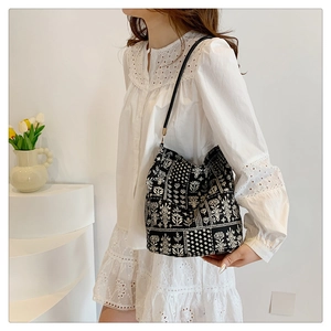 Sac fourre-tout chic à fleurs noir et blanc porté par un mannequin en décor épuré