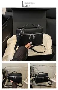 Detail view of black lychee grain leather lunchbox bag with silver zippers and top handle
