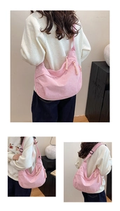 Detail of pink corduroy dumpling bag featuring ribbed texture and woven zipper pull