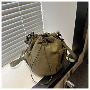 Detail of army green nylon crossbody bag with drawstring closure and mesh side pockets