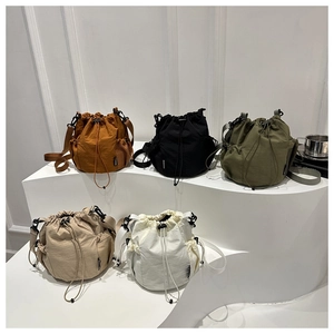 Close-up of five colorful nylon bucket bags with side mesh pockets on a minimalist stand