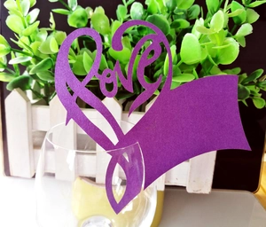 Detail view of purple glitter heart-shaped place card with hollow LOVE design on a glass