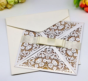 Elegant white lace laser-cut invitation card with a gold inner page and cream ribbon bow