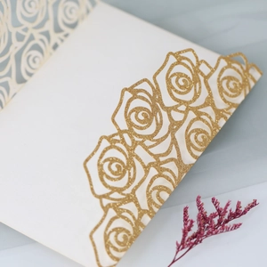 Detail of laser-cut rose hollow design with golden glitter on elegant wedding invitation