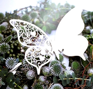 Macro detail of white laser-cut butterfly card with intricate heart-shaped hollow patterns