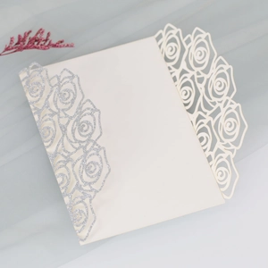 Detail showing the laser-cut rose patterns and silver glitter on the wedding invitation