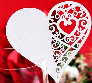 Macro view of laser-cut heart seat card with white glitter finish and hollow scroll pattern