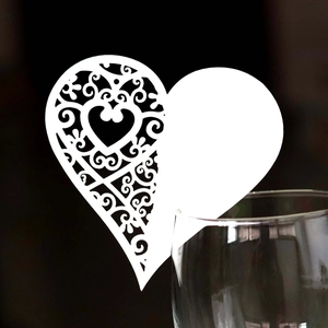 Close-up of white heart laser-cut place card with hollow pattern on a glass rim