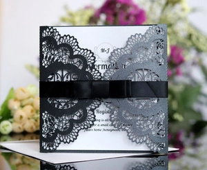 Laser-cut wedding invitation with black silk ribbon bow and shimmer grey laser-cut design