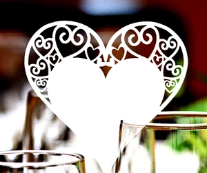 Detailed laser-cut white heart place card with intricate patterns for wedding decor