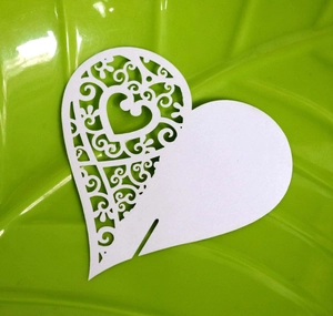 Close-up of laser-cut heart place card with intricate patterns on green tray