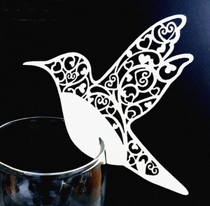 Detailed laser-cut hummingbird place card with heart patterns for wedding wine glasses