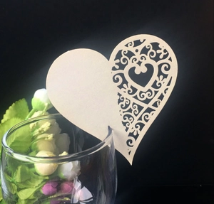 Detailed laser-cut heart place card in cream white with intricate floral scrollwork patterns