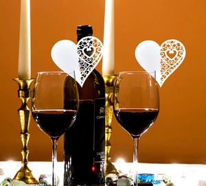 White heart laser-cut paper wine glass card with intricate floral lace for wedding tables